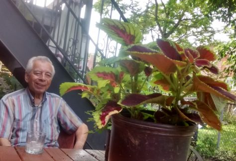 Alfonso Plasencia is relaxing at a picnic table in his backyard garden, located in East Elmhurst, 2016. Donated to Queens Memory: Memories of Migration by Walter Saavedra.