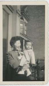 A smiling Minnie Chan holds a pouting Ellyn Chan in her arms, 1945. Donated to Queens Memory Collection at the Archives at Queens Public Library.